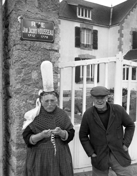 Couple bigouden devant le 15, rue Jean-Jacques Rousseau à Penmarch. La femme confectionne une résure en picot bigouden.